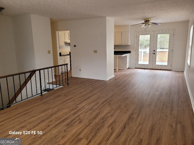 unfurnished living room featuring french doors, a textured ceiling, ceiling fan, and dark hardwood / wood-style floors