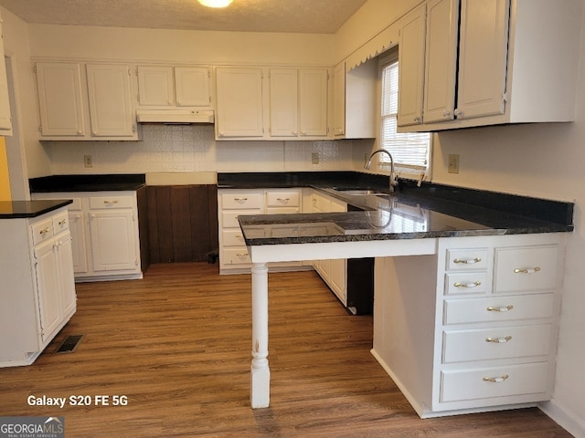 kitchen featuring sink, wood-type flooring, white cabinetry, and kitchen peninsula