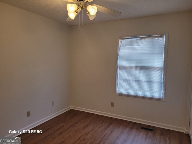 spare room with ceiling fan, a wealth of natural light, and dark hardwood / wood-style floors