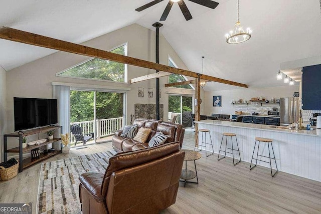 living room with ceiling fan with notable chandelier, light hardwood / wood-style flooring, and high vaulted ceiling