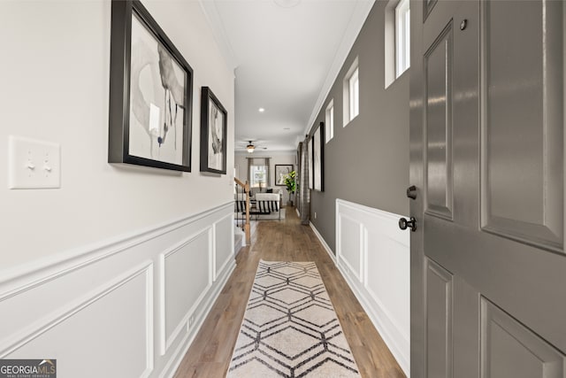 corridor with ornamental molding and light hardwood / wood-style floors