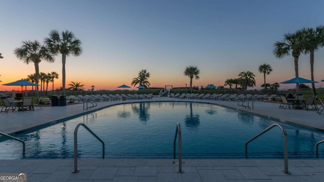 pool at dusk with a patio area