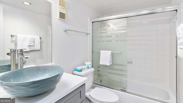 full bathroom featuring bath / shower combo with glass door, vanity, and toilet