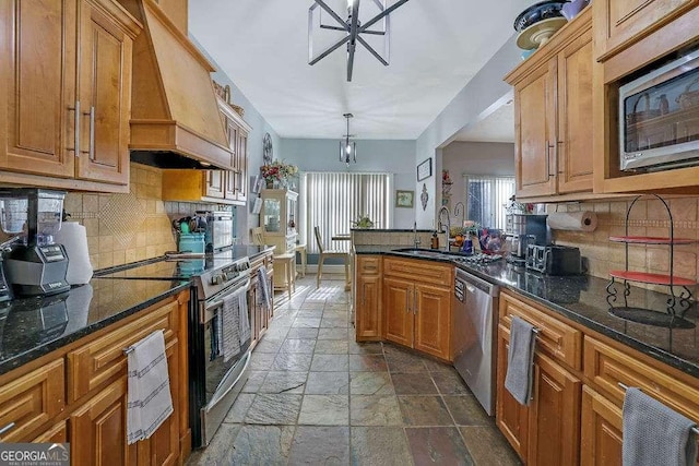 kitchen featuring stainless steel appliances, custom range hood, decorative backsplash, sink, and decorative light fixtures