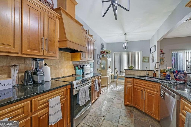 kitchen with premium range hood, decorative light fixtures, stainless steel appliances, dark stone countertops, and sink