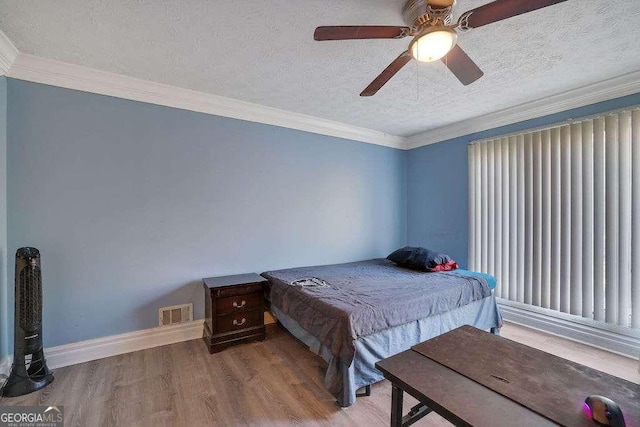 bedroom featuring wood-type flooring, a textured ceiling, ceiling fan, and crown molding