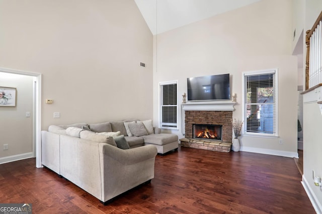 living room with high vaulted ceiling, dark wood-type flooring, and a stone fireplace