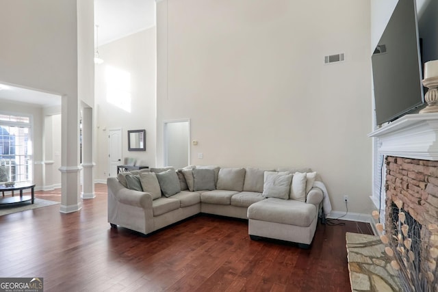 living room featuring a towering ceiling, a fireplace, and dark wood-type flooring