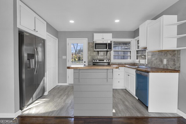 kitchen with sink, white cabinetry, appliances with stainless steel finishes, and butcher block counters