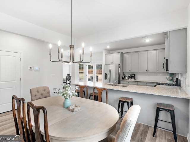 dining space with sink, a notable chandelier, and light wood-type flooring