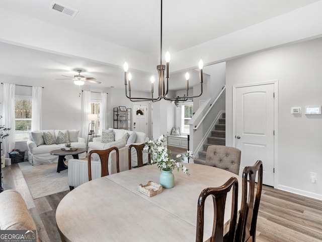 dining room with ceiling fan with notable chandelier and hardwood / wood-style floors