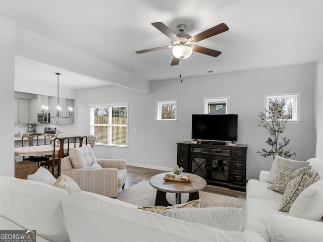 living room featuring ceiling fan with notable chandelier and light wood-type flooring