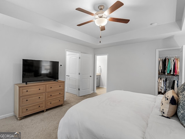 bedroom with ceiling fan, a raised ceiling, light carpet, and a closet