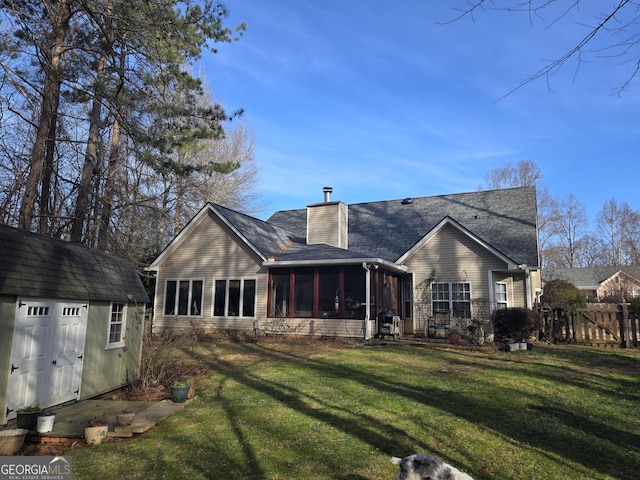 rear view of house featuring a storage unit, a sunroom, and a lawn