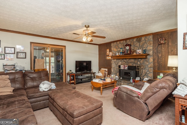 living room with a textured ceiling, ceiling fan, crown molding, wood walls, and light colored carpet