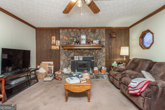 carpeted living room featuring a wood stove, ornamental molding, ceiling fan, a textured ceiling, and wooden walls