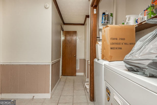 washroom featuring light tile patterned floors, separate washer and dryer, a textured ceiling, and ornamental molding