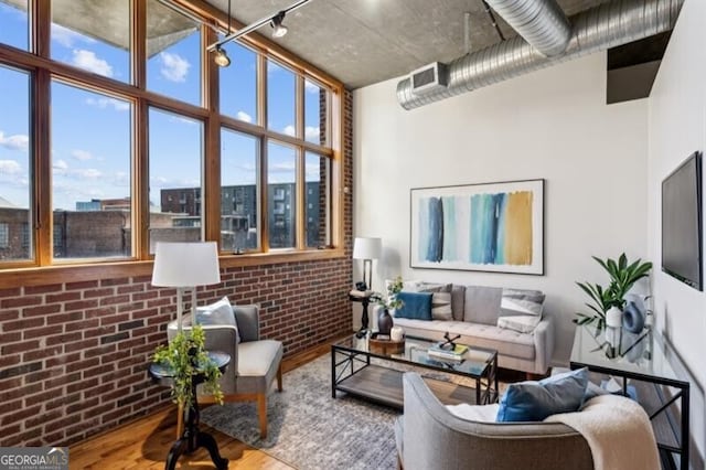 living room featuring hardwood / wood-style flooring and brick wall