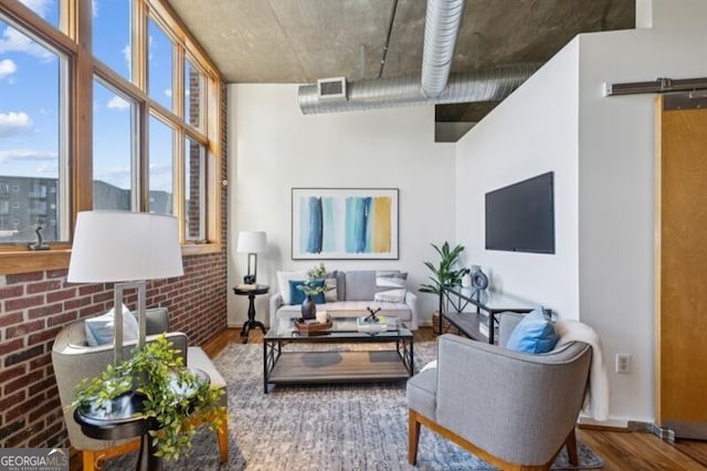 living room with wood-type flooring and brick wall