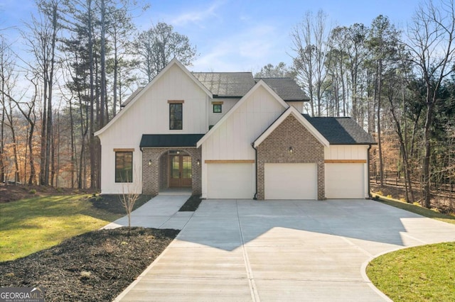 modern farmhouse with brick siding, french doors, a garage, and driveway