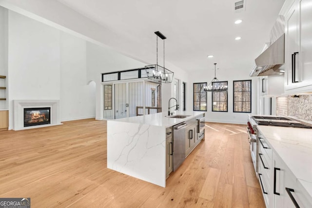 kitchen with visible vents, an inviting chandelier, a sink, appliances with stainless steel finishes, and a glass covered fireplace