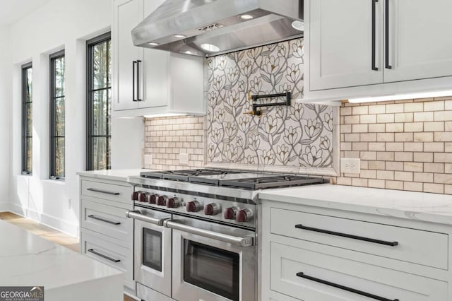 kitchen featuring extractor fan, range with two ovens, light stone countertops, and tasteful backsplash