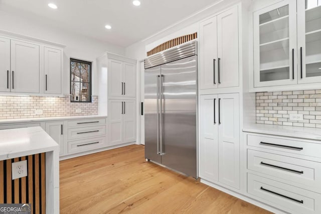 kitchen with recessed lighting, white cabinets, glass insert cabinets, light wood-style floors, and built in refrigerator