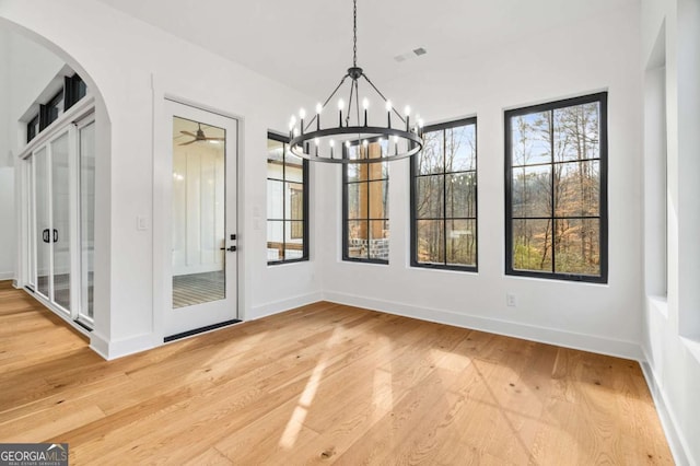 unfurnished dining area with visible vents, baseboards, light wood-style flooring, and ceiling fan with notable chandelier