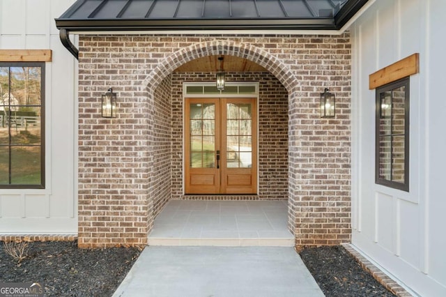 entrance to property featuring brick siding, french doors, metal roof, and a standing seam roof