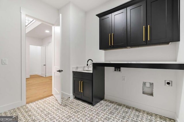 kitchen featuring a sink, baseboards, dark cabinets, and light countertops