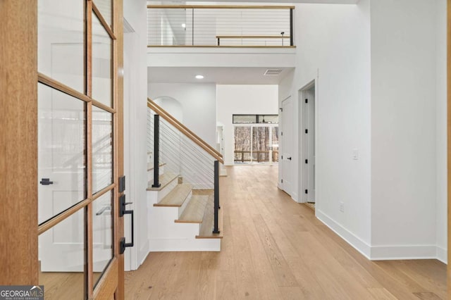 foyer entrance featuring stairway, baseboards, wood finished floors, and a towering ceiling