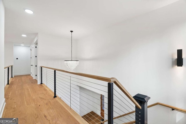 hall featuring an upstairs landing, recessed lighting, an inviting chandelier, and wood finished floors