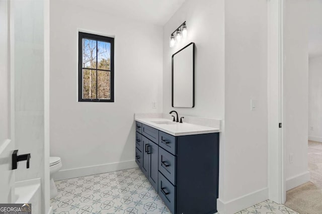 full bathroom with toilet, vanity, and baseboards