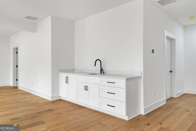 bar with a sink, visible vents, baseboards, and light wood-style floors