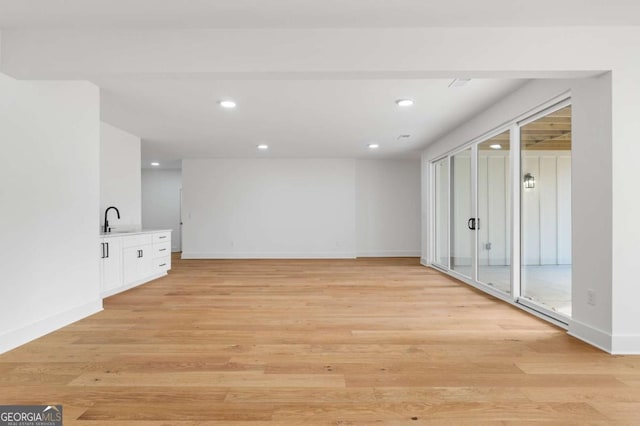 spare room featuring recessed lighting, light wood-style flooring, baseboards, and a sink