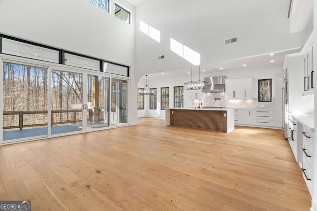 unfurnished living room featuring visible vents, light wood-style floors, and a healthy amount of sunlight