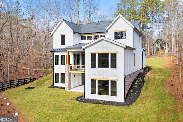 rear view of house with fence, a standing seam roof, a shingled roof, a lawn, and board and batten siding