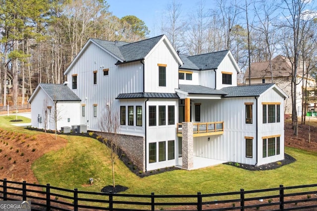 back of house featuring a yard, a standing seam roof, and roof with shingles