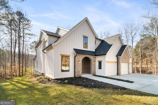 modern farmhouse style home featuring a front yard, a standing seam roof, concrete driveway, a garage, and brick siding