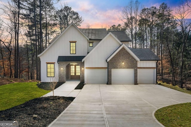 modern farmhouse style home featuring a front yard, roof with shingles, concrete driveway, a garage, and brick siding