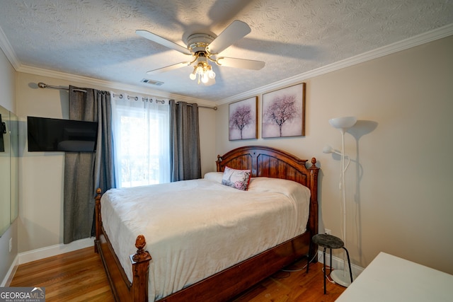 bedroom featuring ceiling fan, ornamental molding, a textured ceiling, and wood-type flooring