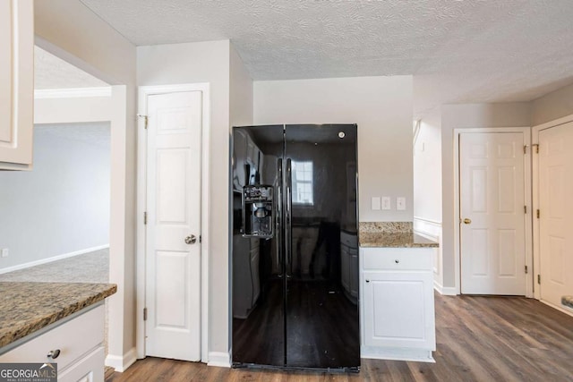 kitchen featuring white cabinets, black fridge with ice dispenser, light stone countertops, and a textured ceiling