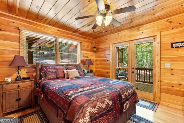 bedroom featuring wood ceiling, wood walls, hardwood / wood-style flooring, ceiling fan, and access to exterior