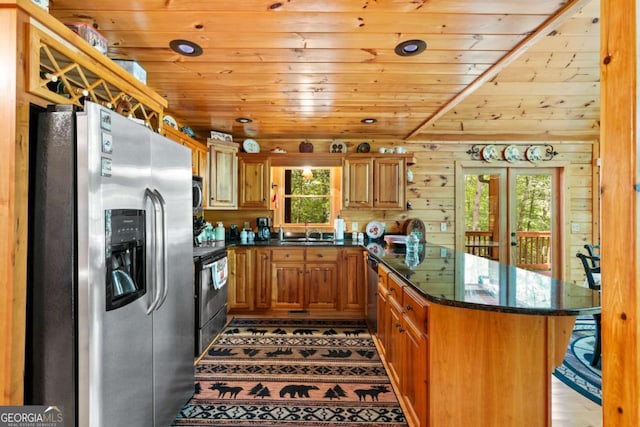 kitchen with wooden walls, wooden ceiling, appliances with stainless steel finishes, dark stone counters, and sink