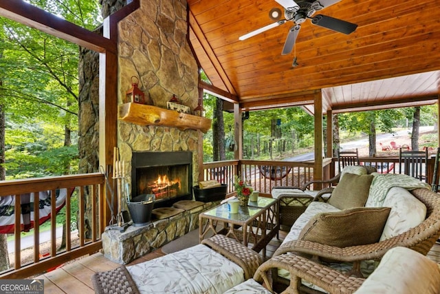 sunroom / solarium featuring vaulted ceiling, wooden ceiling, an outdoor stone fireplace, and ceiling fan