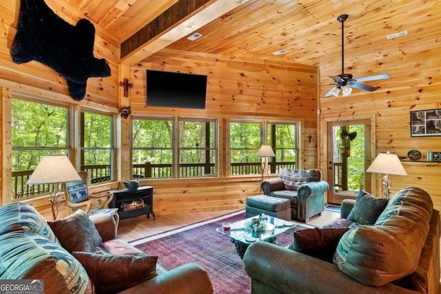 living room with a high ceiling, wood ceiling, wood-type flooring, a wood stove, and ceiling fan