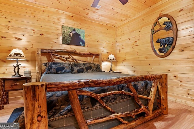 bedroom with ceiling fan, wood ceiling, wood walls, and light hardwood / wood-style flooring