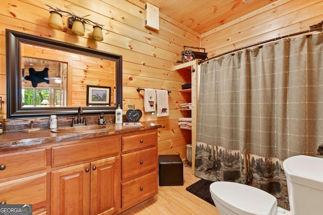 bathroom with hardwood / wood-style floors, vanity, wooden walls, toilet, and walk in shower