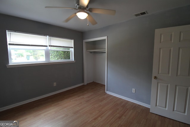 unfurnished bedroom with ceiling fan, light wood-type flooring, and a closet