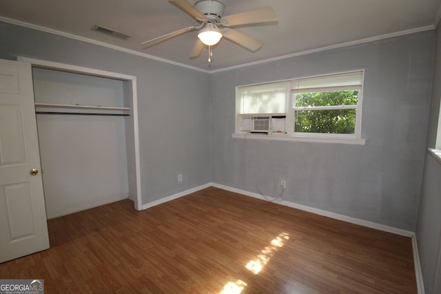 unfurnished bedroom with ceiling fan, ornamental molding, a closet, and hardwood / wood-style flooring